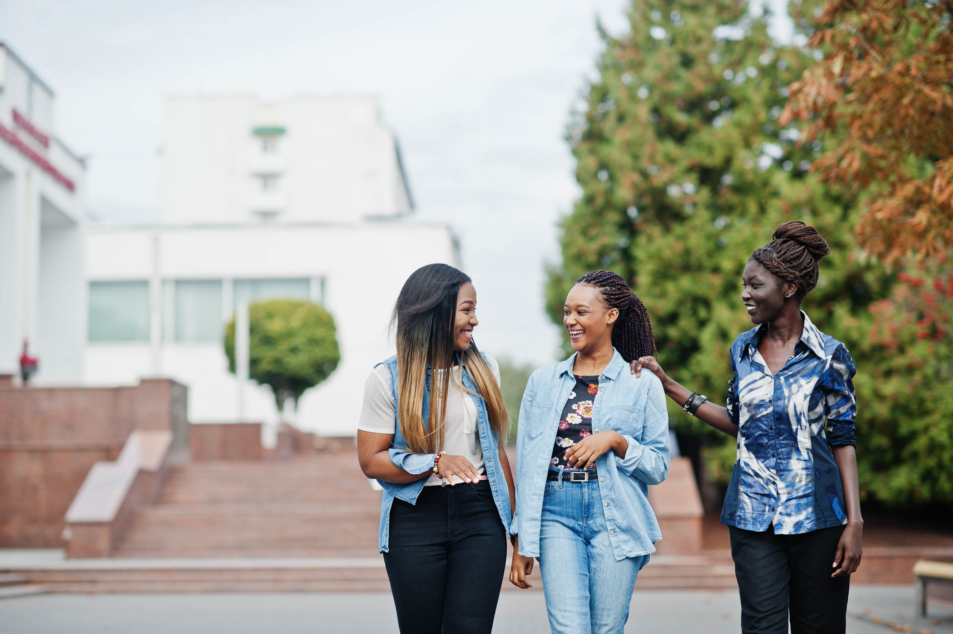 3 students walking through campus and laughing with each other